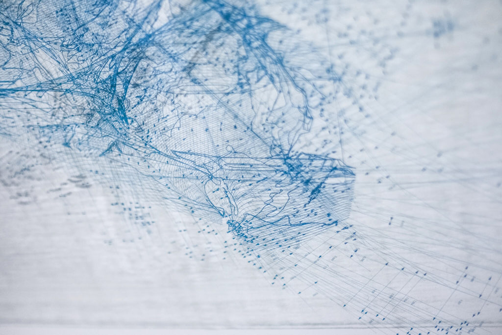 A close-up of a work from Nesbit's "phlatness" series involving a collection of delicate, blue lines, arrows, and numbers, that tangle and congregate towards the upper-left of the image and loosen into more coherent strands on the lower right. Etched onto lithograph paper through a scripted and iterative process.