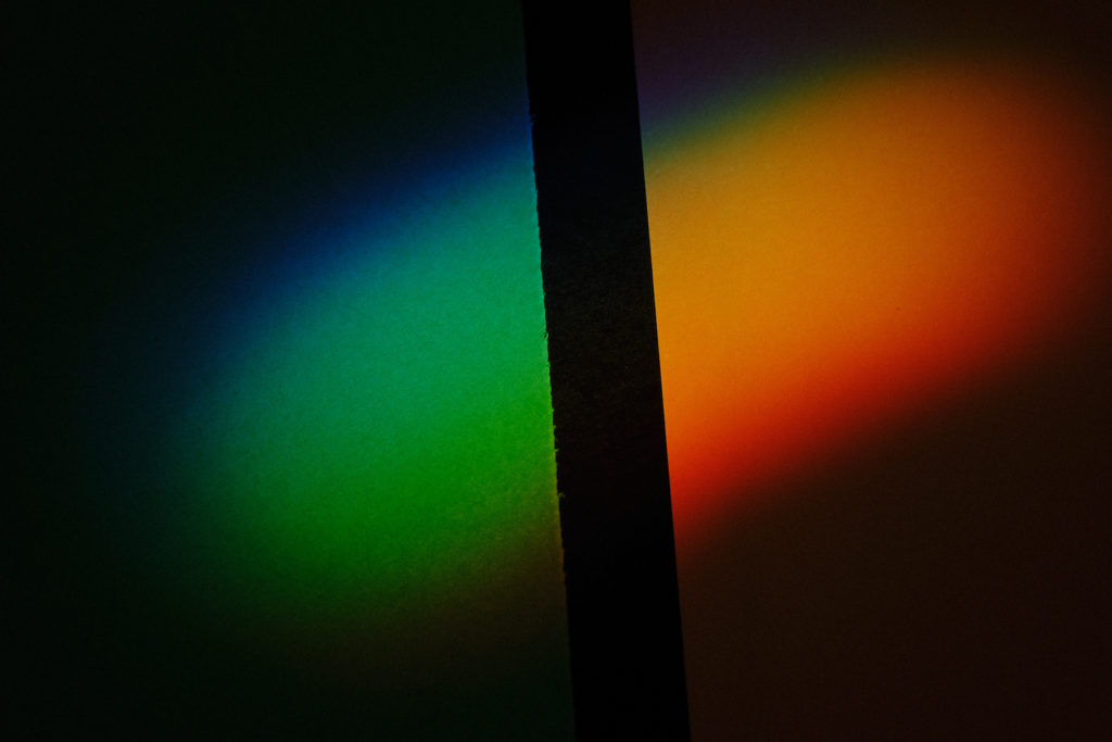 Dark and moody photograph of color spectrum cast on architectural details.