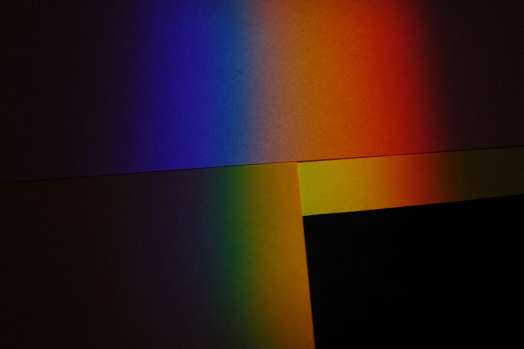 Dark and moody photograph of color spectrum cast on architectural details.